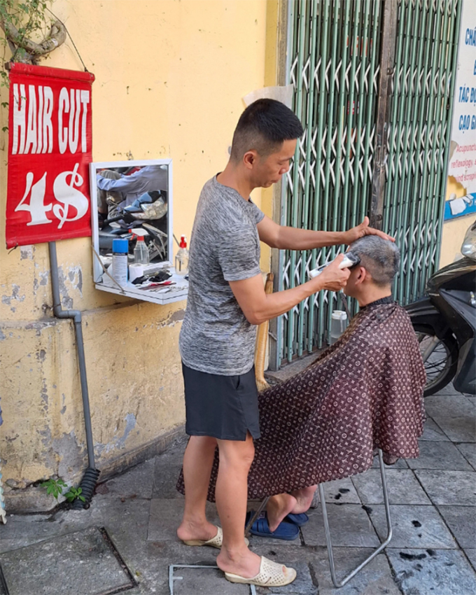 Thợ cắt tóc đang cạo đầu cho khách. Ảnh: SCMP